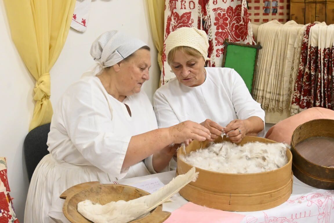 Members in traditional dress processing wool by hand